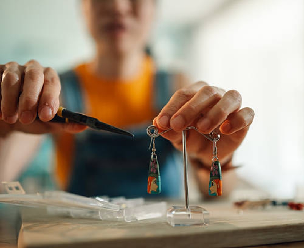 Close-up of artisan using pliers, crafting unique earrings with polymer clay, showcasing creativity and craftsmanship in jewelry making